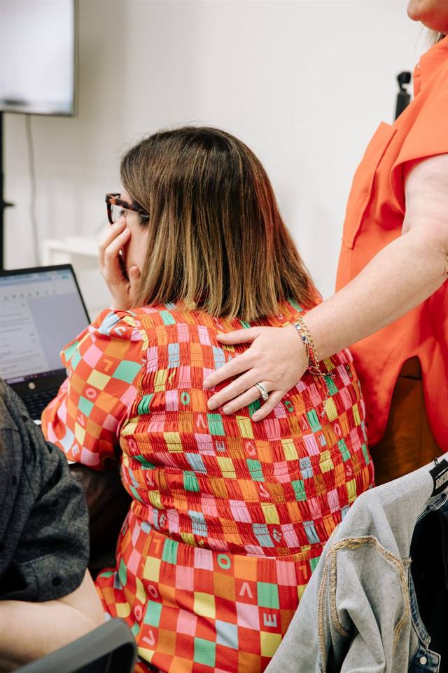 Sandra with her hand on the back of a woman at her laptop during a Claude training day in Norwood