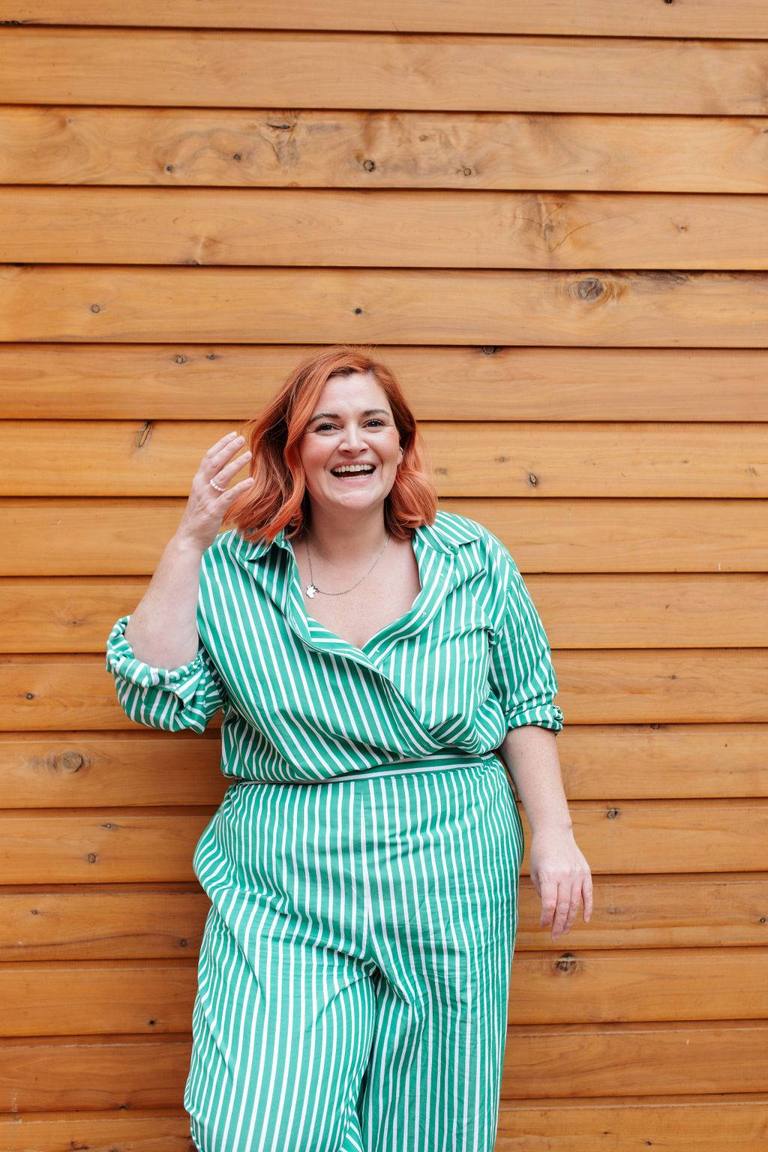 Sandra Senn, founder of Business Mums Hub, laughing in front of a timber wall