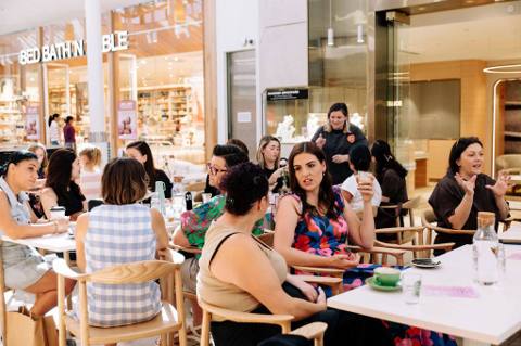 A full room of women at cafe tables during an Open Coffee event