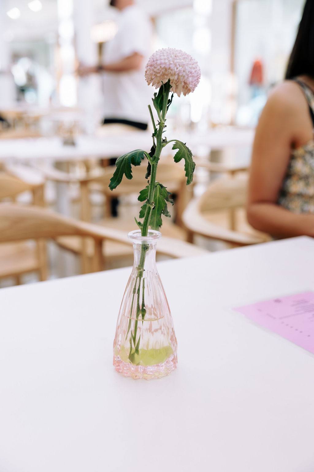 A single flower in a vase on an empty cafe table