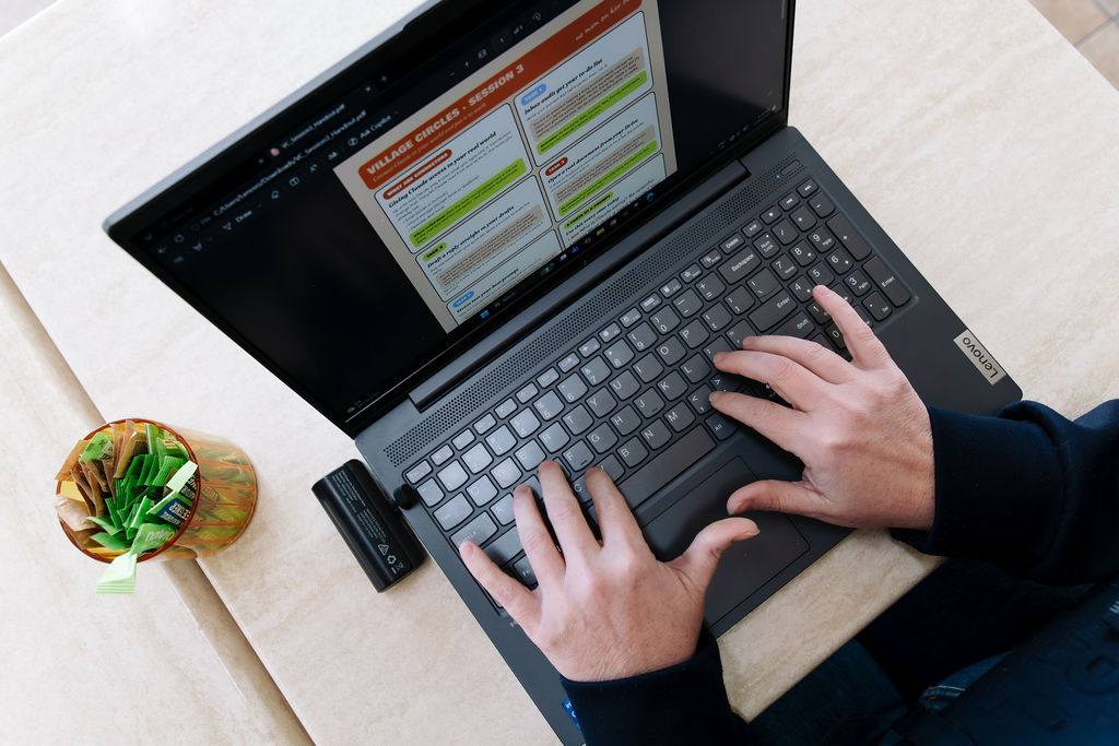 Working on a laptop with a Village Circles session handout on screen