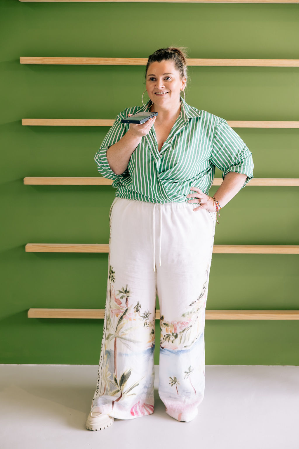 Sandra Senn, who teaches Claude Code in Adelaide, talking into her phone against a green wall